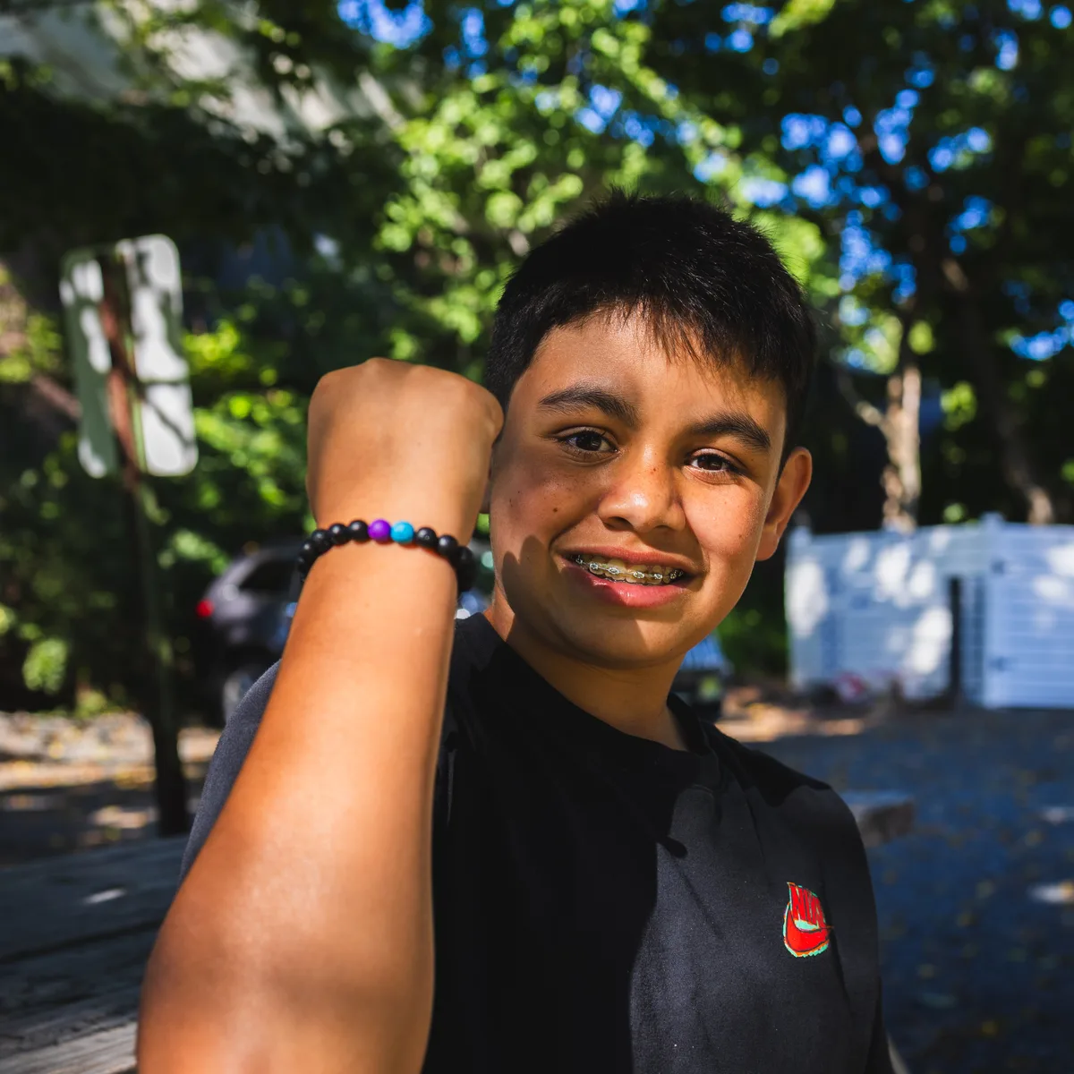 Deven, the founder of Volcanic Vibes, smiling and holding up his wrist wearing one of his handmade bracelets