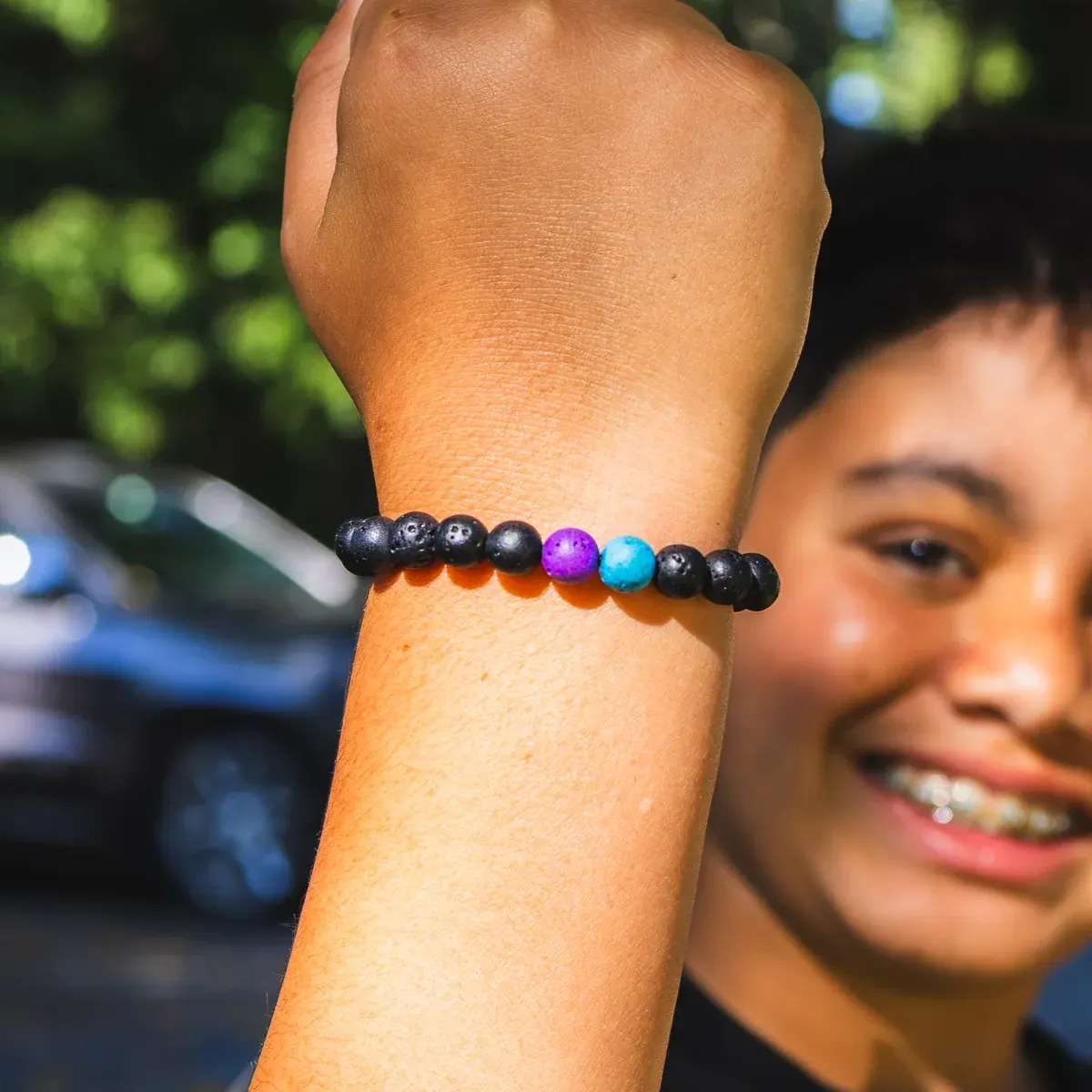 Deven holding up his wrist to show a Volcanic Vibes bracelet with purple and turquoise accent beads